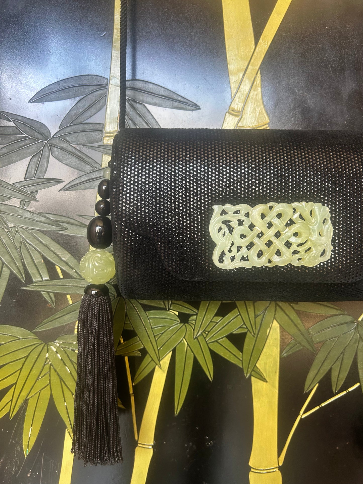 black hard case purse with carved jade tone accents and tassel