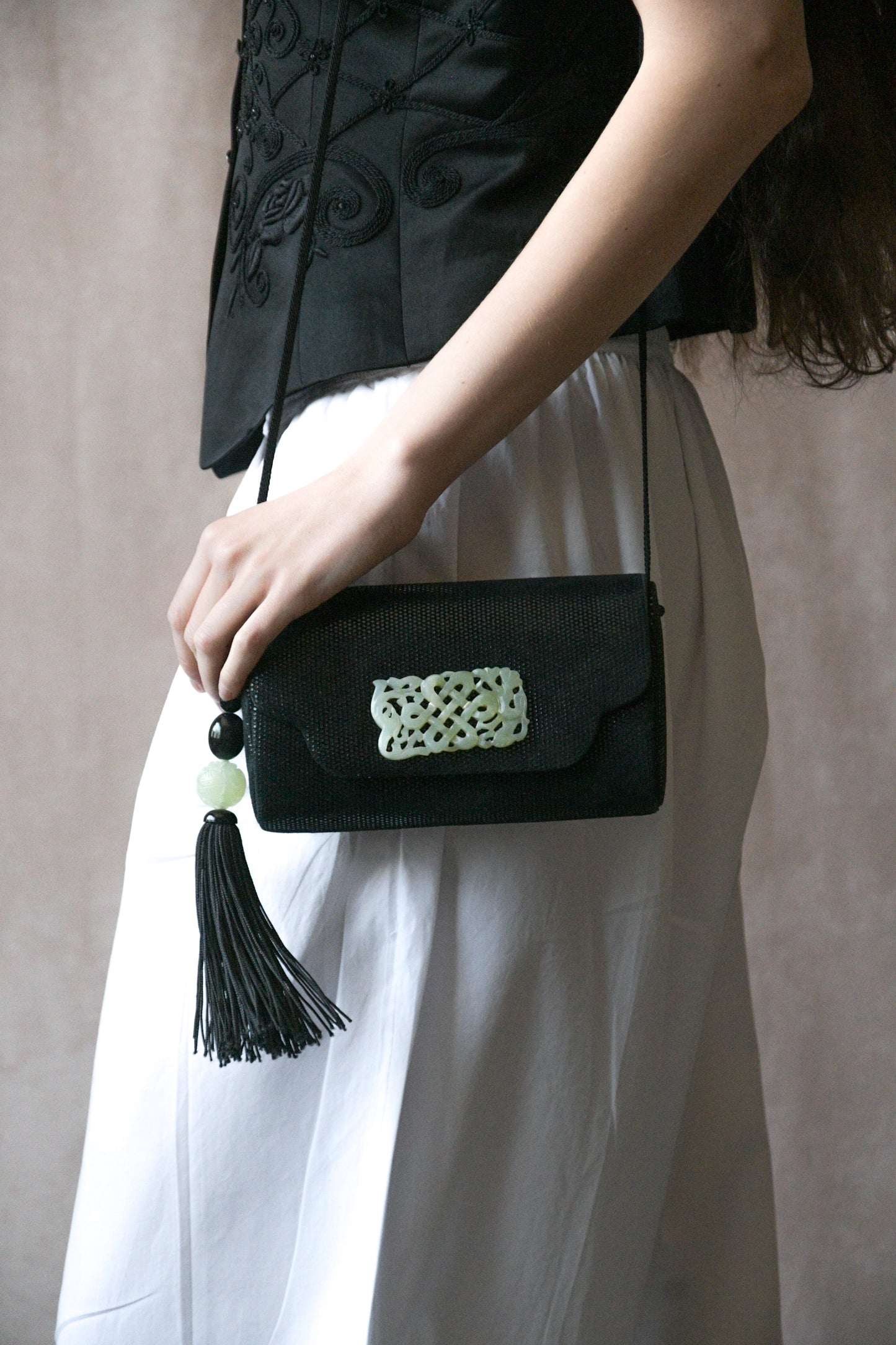 black hard case purse with carved jade tone accents and tassel