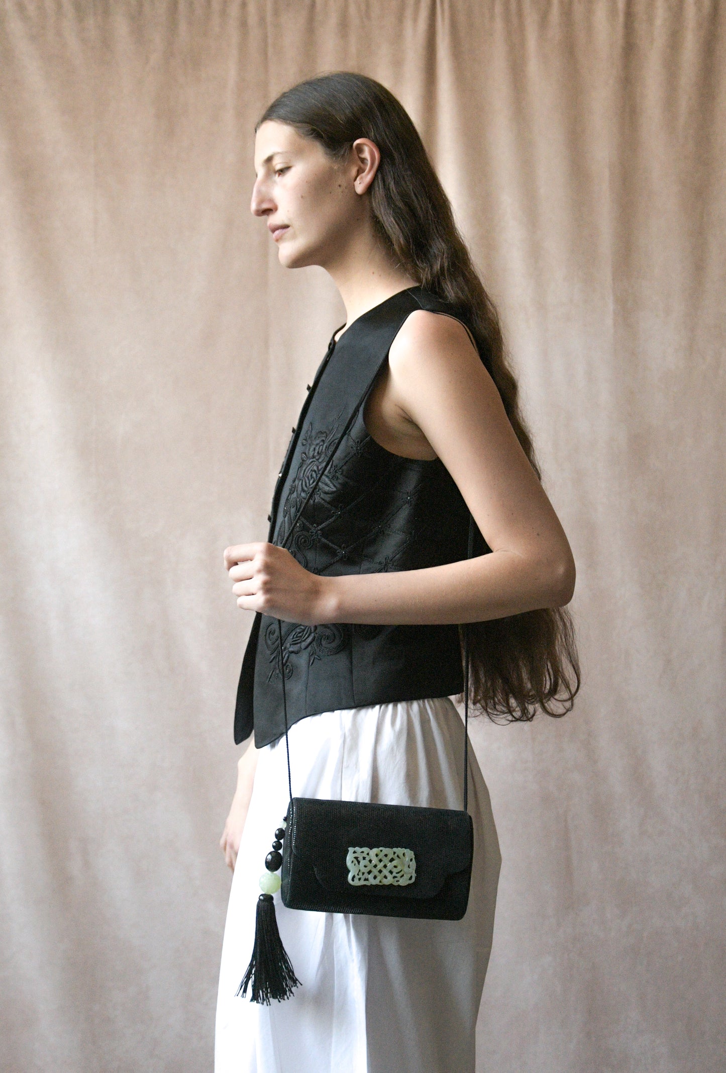 black hard case purse with carved jade tone accents and tassel