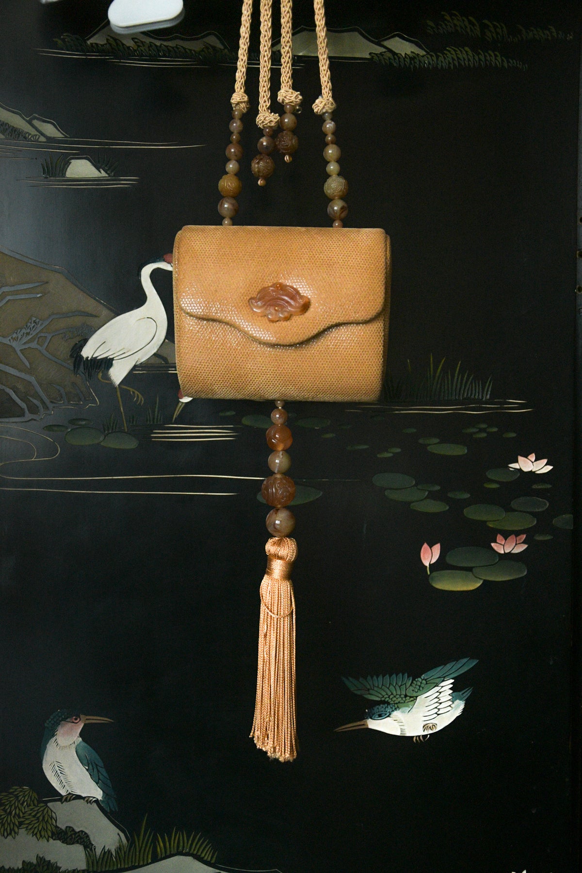 hard case purse with carved jade tone accents and tassel